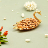 Decorative swan bowl filled with almonds on a light green background with flowers.
